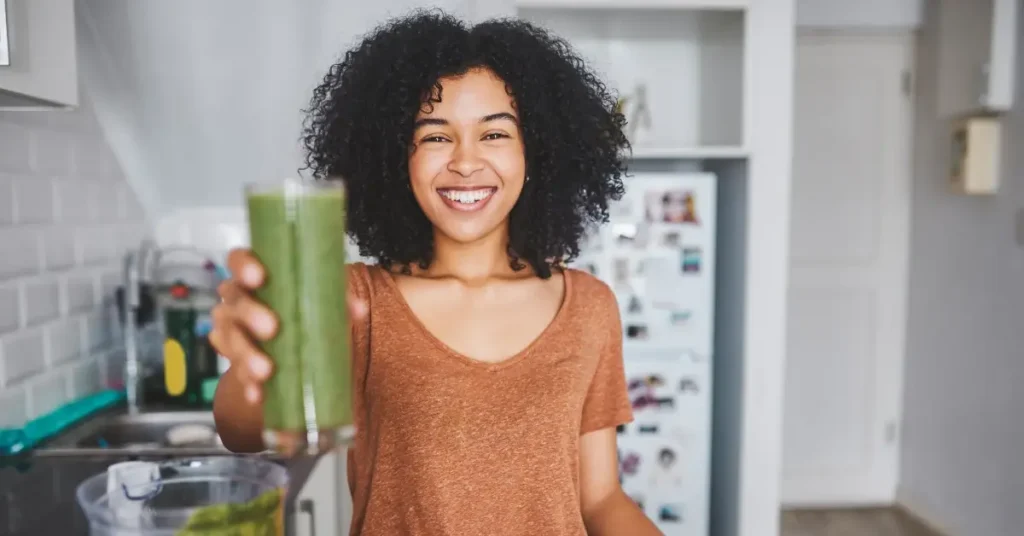 best juice to drink in the morning + A woman is holding a juice in her hand and handing it over