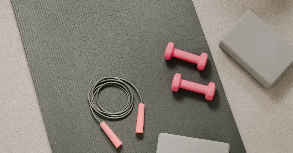 beginner pilates workout + On the floor, there is a workout mat and dumbbell