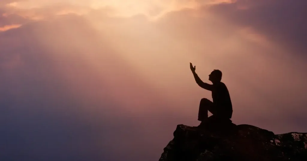 good morning prayer for him + A person sits on a mountain, stretches their arms upward, and prays