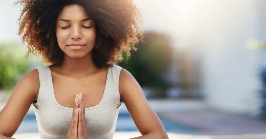 pilates workout at home + A woman has her eyes closed, holds her hands to her heart, and expresses gratitude